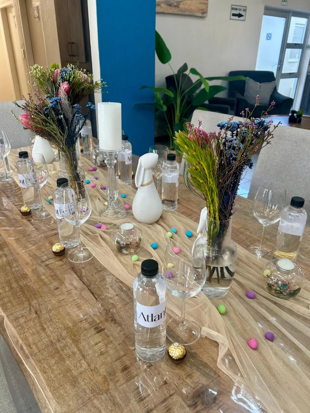 Easter brunch table with proteas, candles and Atlantic Edge water